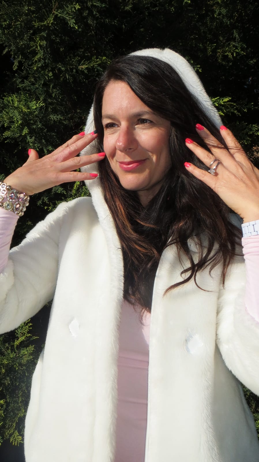 Cream faux fur hooded jacket worn over a pale pink long-sleeved top